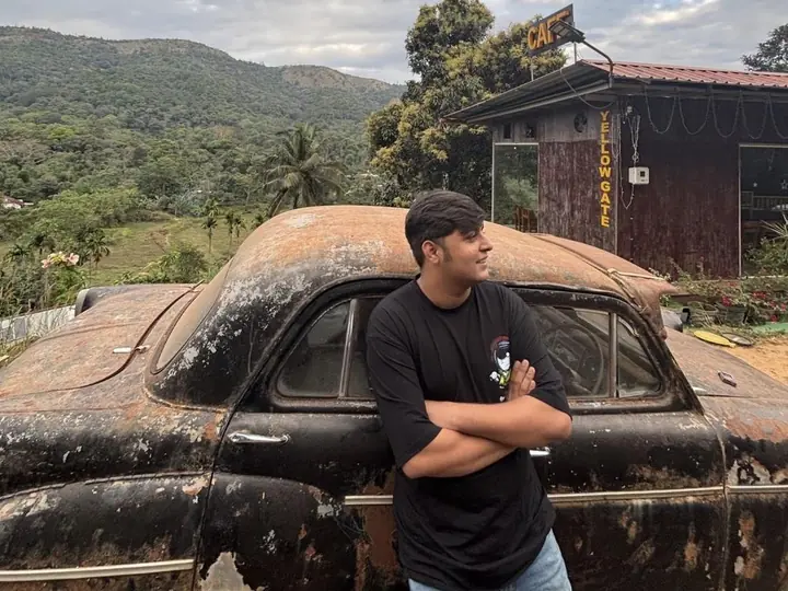 Abhijay leaning on a vintage car in the hills