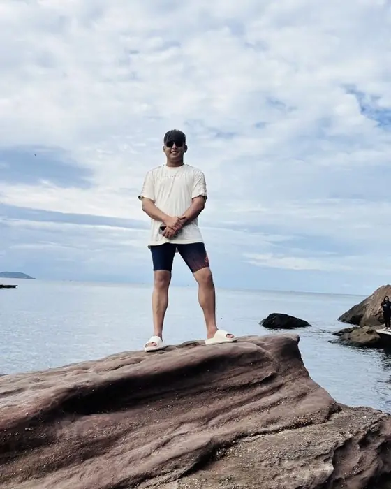 Abhijay standing on a rock by the sea